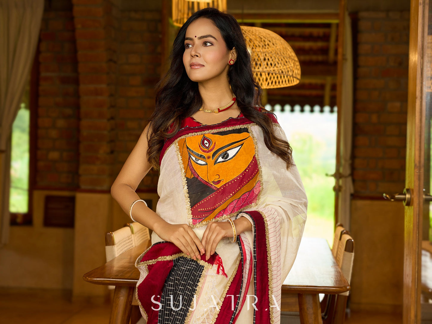 Striking white cotton saree with bold red-black borders, featuring a hand-painted Durga motif