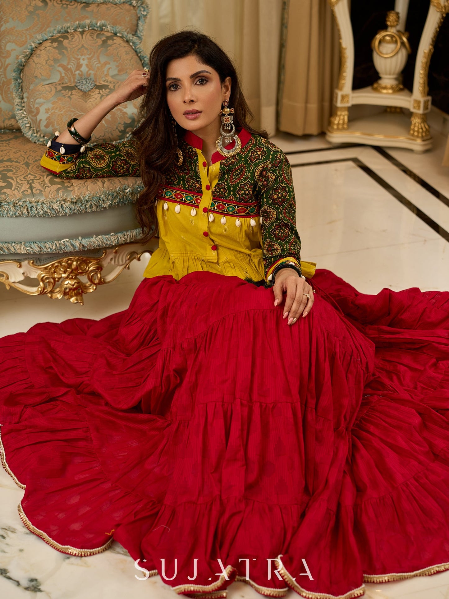 Red tiered Jamdani lehenga with a striking green Ajrakh and mustard jamdani choli featuring intricate mirror work & shell tassels .