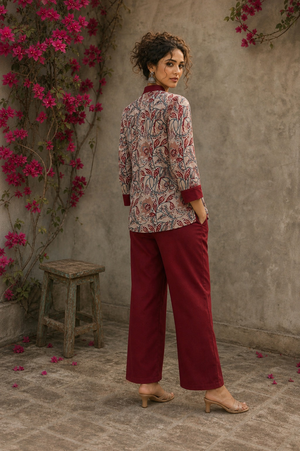 Elegant maroon floral top with intricate maroon pleats, high neckline, covered buttons, and coordinating sleeve cuffs.