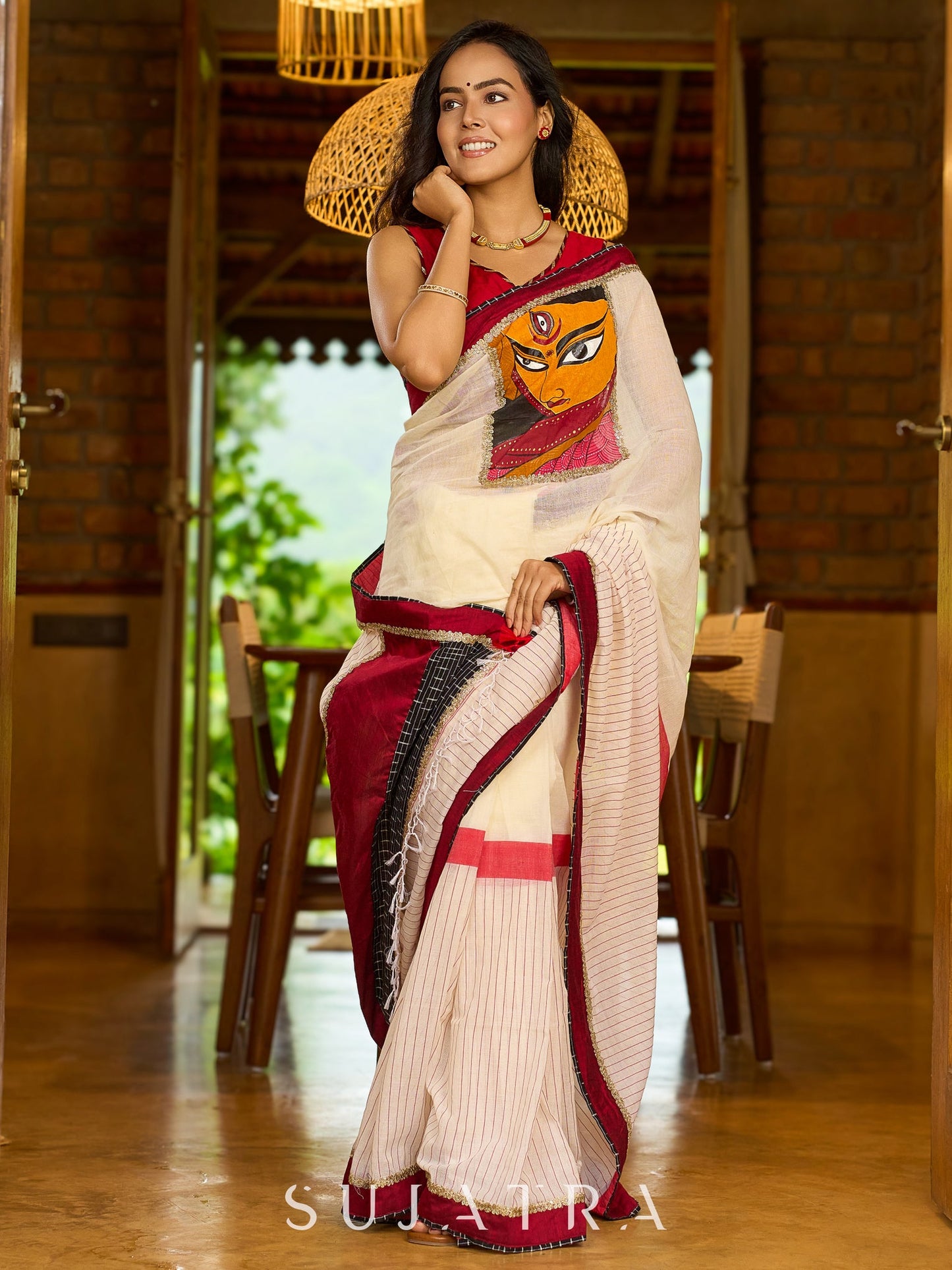 Striking white cotton saree with bold red-black borders, featuring a hand-painted Durga motif