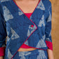 Deep indigo jacket with an asymmetric front closure, magenta folded cuffs, and coordinated accents, offering a structured silhouette with bold contrast and a refined look for elevated corporate styling.
