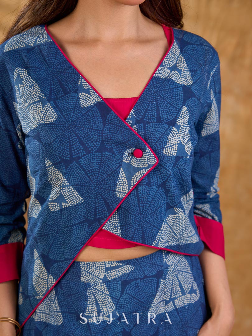 Deep indigo jacket with an asymmetric front closure, magenta folded cuffs, and coordinated accents, offering a structured silhouette with bold contrast and a refined look for elevated corporate styling.