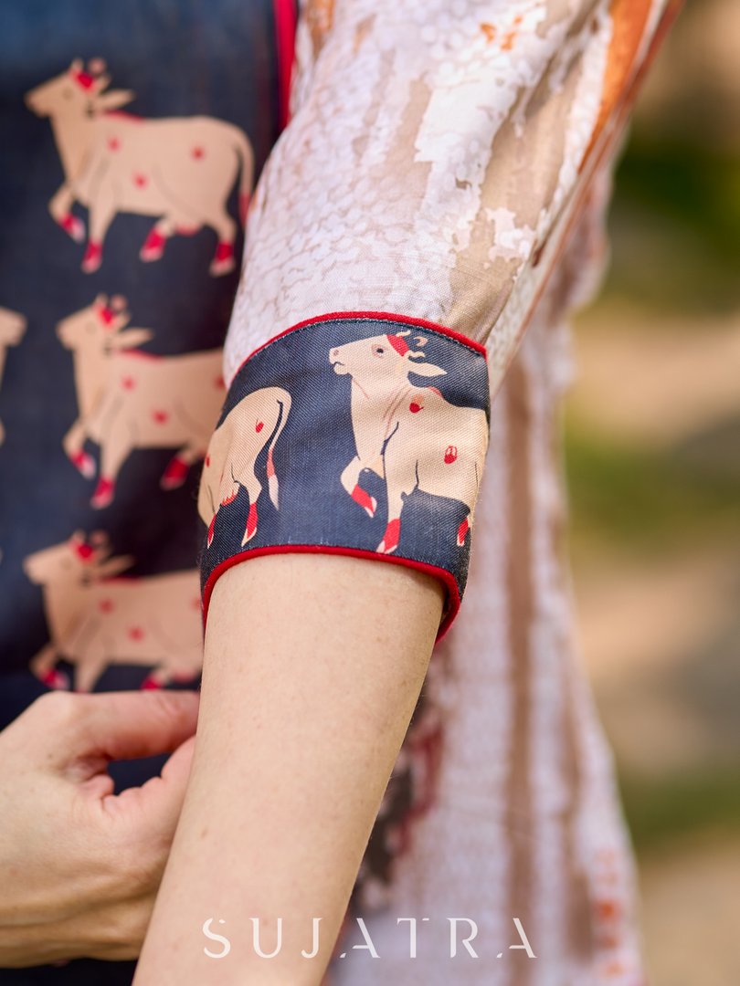 Artisanal off-white kurta showcasing Pichwai-inspired cow artwork highlighted with classic red tones