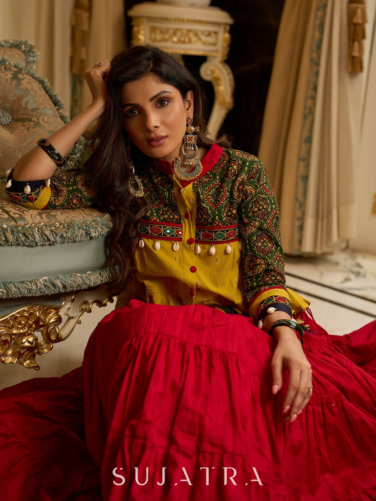 Red tiered Jamdani lehenga with a striking green Ajrakh and mustard jamdani choli featuring intricate mirror work & shell tassels .