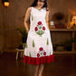 White sleeveless dress featuring red butta motifs and a gathered red panel at the hem, finished with coordinated red accents for a fresh, playful silhouette with a touch of traditional charm.