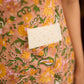 Summery mustard and peach floral sleeveless dress featuring a boat neckline and Hakoba pocket detailing, finished with soft off-white accents for a breezy, cheerful silhouette perfect for warm days.