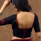 Timeless black blouse elevated by red intricate embroidery , adding a pop of colour .