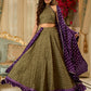 Vibrant Mehendi green and purple bandhani lehenga paired with a mirror work halter neck choli and matching dupatta.
