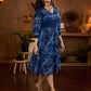 Indigo printed dress featuring dragonfly motifs, gathered sleeves with cuffs, and navy blue pleated waist detailing accented with pearls, creating a graceful silhouette with refined artisanal charm.