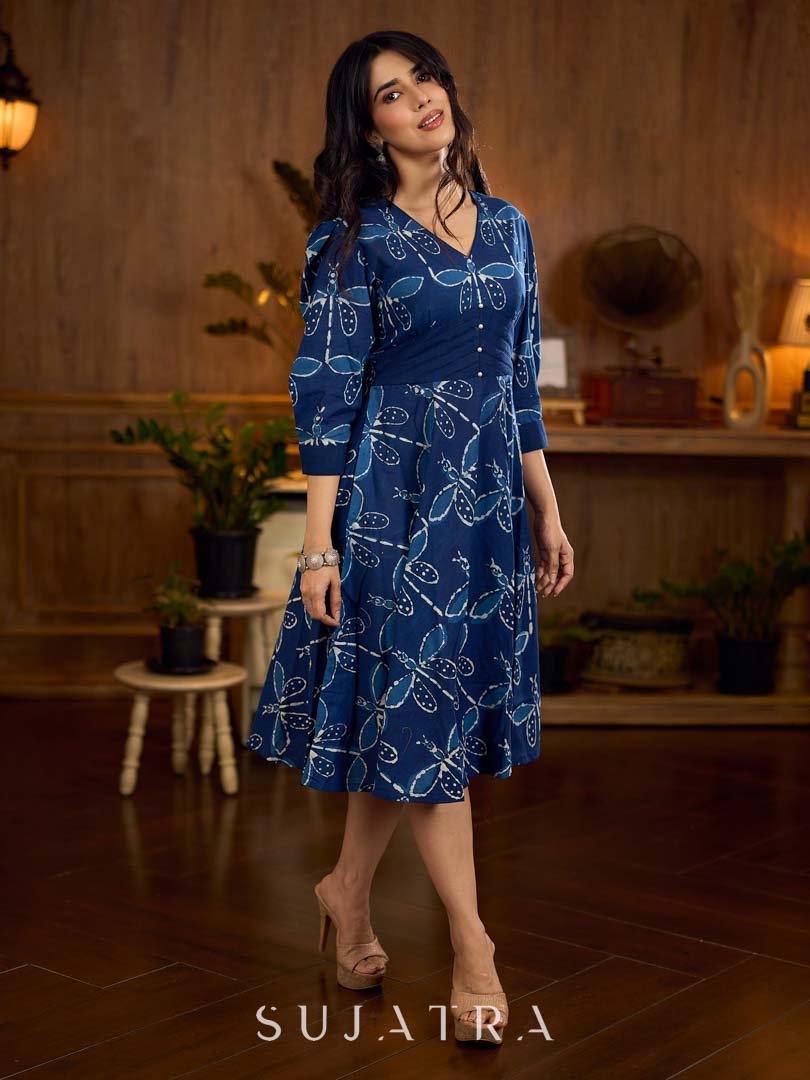Indigo printed dress featuring dragonfly motifs, gathered sleeves with cuffs, and navy blue pleated waist detailing accented with pearls, creating a graceful silhouette with refined artisanal charm.