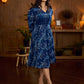 Indigo printed dress featuring dragonfly motifs, gathered sleeves with cuffs, and navy blue pleated waist detailing accented with pearls, creating a graceful silhouette with refined artisanal charm.