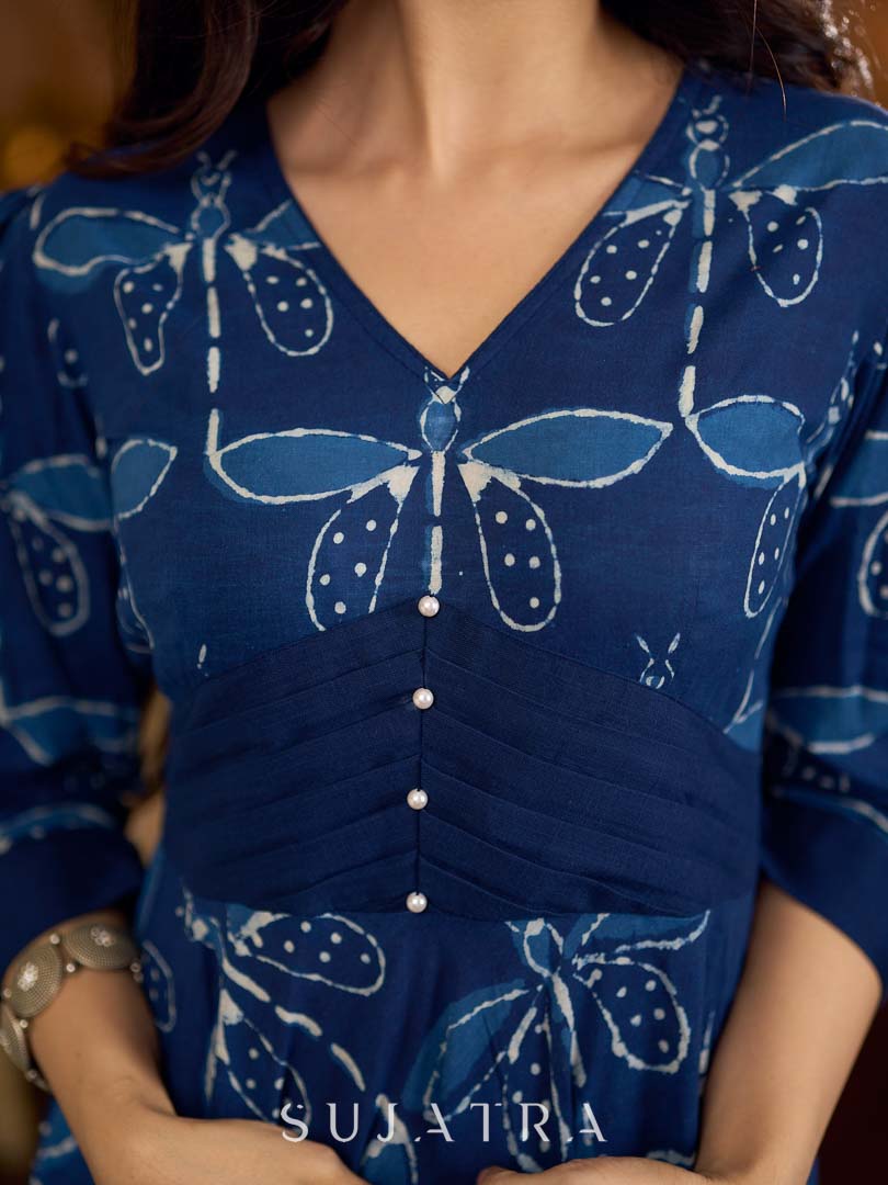 Indigo printed dress featuring dragonfly motifs, gathered sleeves with cuffs, and navy blue pleated waist detailing accented with pearls, creating a graceful silhouette with refined artisanal charm.