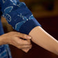 Indigo printed dress featuring dragonfly motifs, gathered sleeves with cuffs, and navy blue pleated waist detailing accented with pearls, creating a graceful silhouette with refined artisanal charm.