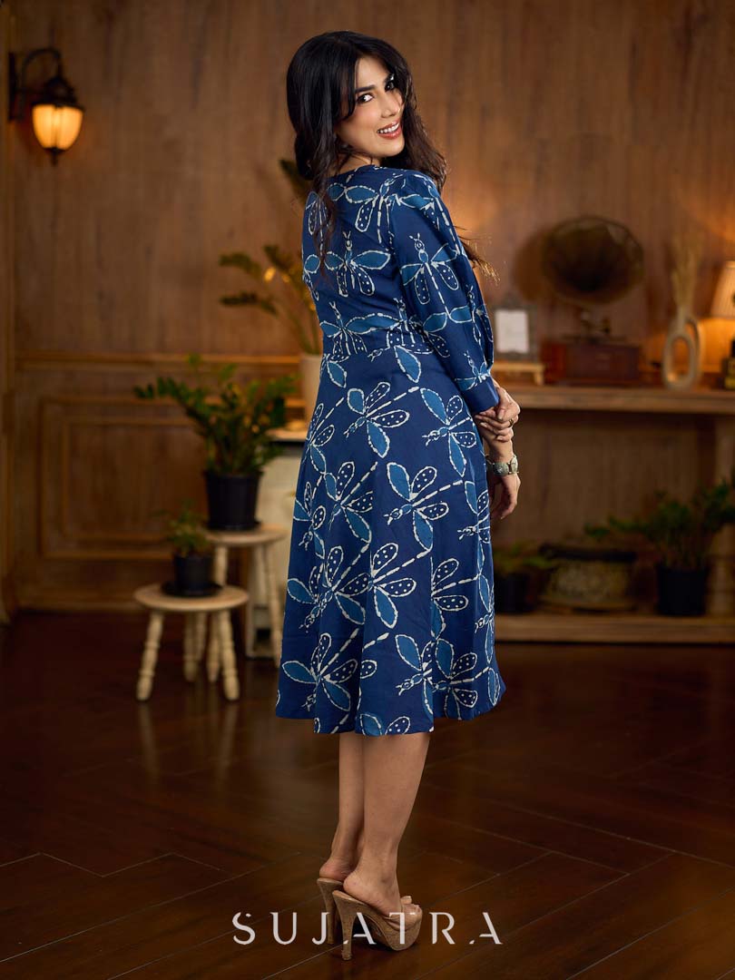 Indigo printed dress featuring dragonfly motifs, gathered sleeves with cuffs, and navy blue pleated waist detailing accented with pearls, creating a graceful silhouette with refined artisanal charm.