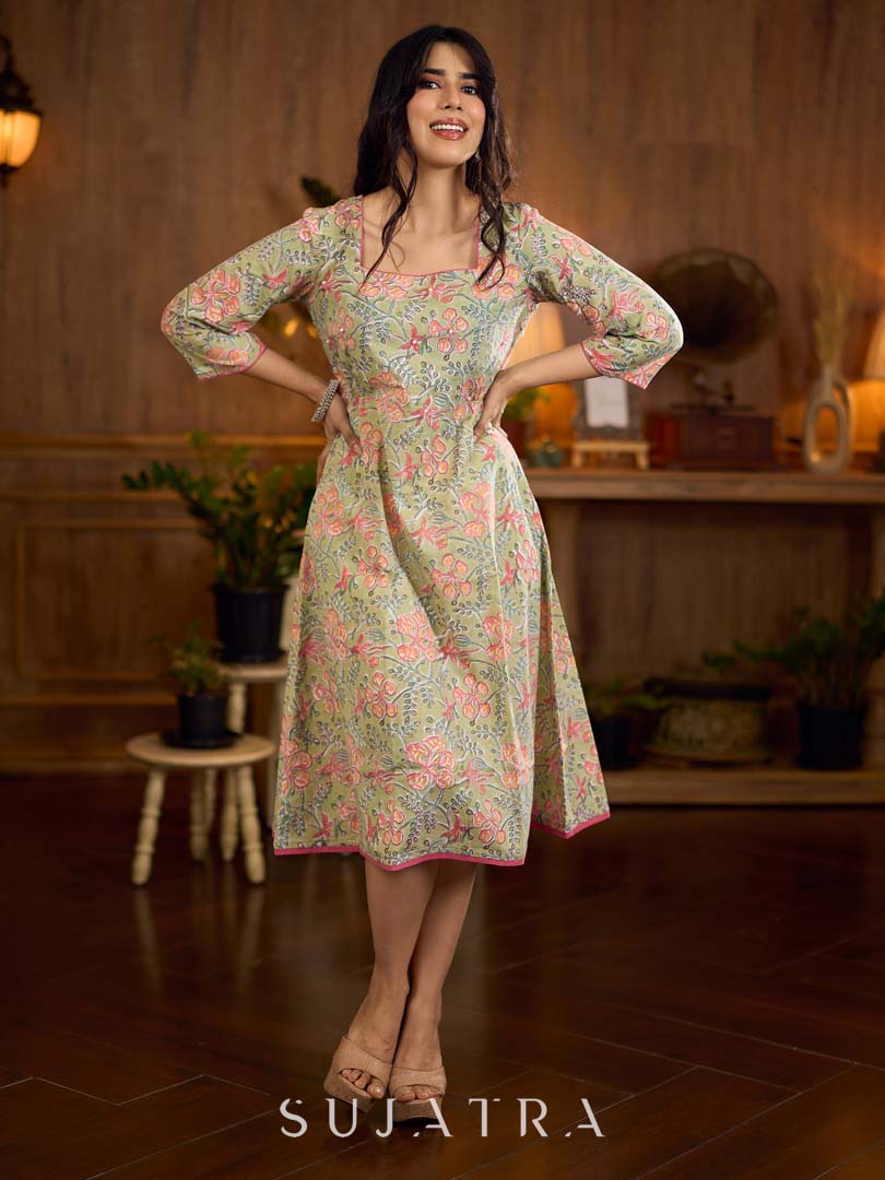 Soft green Gulmohar-printed dress featuring a square neckline and pearl-highlighted motifs, finished with an elasticated waist to create a flattering cinched silhouette with effortless charm.