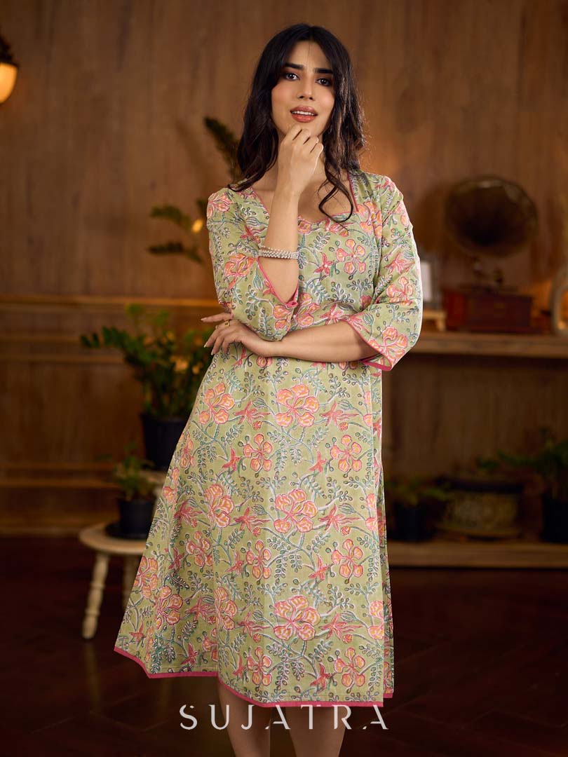 Soft green Gulmohar-printed dress featuring a square neckline and pearl-highlighted motifs, finished with an elasticated waist to create a flattering cinched silhouette with effortless charm.