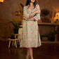 Soft green Gulmohar-printed dress featuring a square neckline and pearl-highlighted motifs, finished with an elasticated waist to create a flattering cinched silhouette with effortless charm.