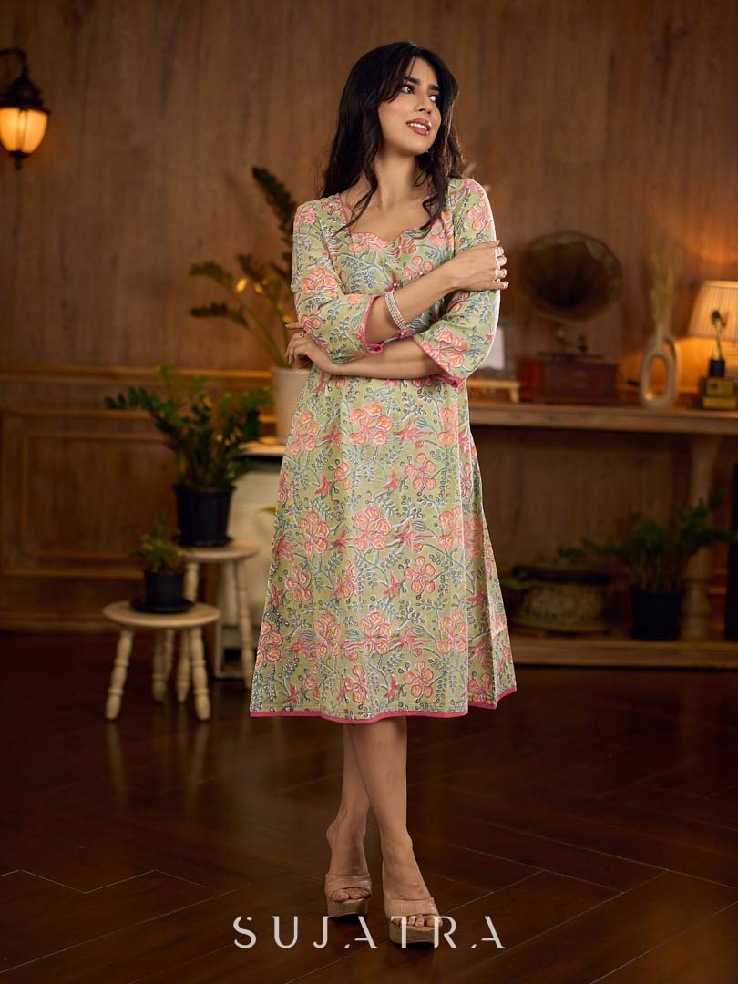 Soft green Gulmohar-printed dress featuring a square neckline and pearl-highlighted motifs, finished with an elasticated waist to create a flattering cinched silhouette with effortless charm.