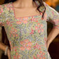 Soft green Gulmohar-printed dress featuring a square neckline and pearl-highlighted motifs, finished with an elasticated waist to create a flattering cinched silhouette with effortless charm.