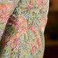 Soft green Gulmohar-printed dress featuring a square neckline and pearl-highlighted motifs, finished with an elasticated waist to create a flattering cinched silhouette with effortless charm.