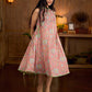 Soft peachy pink floral halter-neck dress with fresh green accents, crafted in a bias-cut silhouette that creates graceful flow and a fluid drape for an effortless summer look.