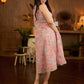 Soft peachy pink floral halter-neck dress with fresh green accents, crafted in a bias-cut silhouette that creates graceful flow and a fluid drape for an effortless summer look.