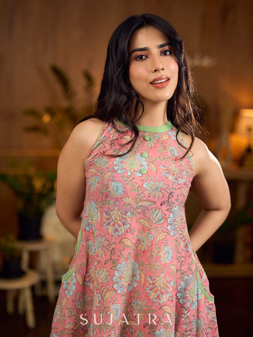Soft peachy pink floral halter-neck dress with fresh green accents, crafted in a bias-cut silhouette that creates graceful flow and a fluid drape for an effortless summer look.