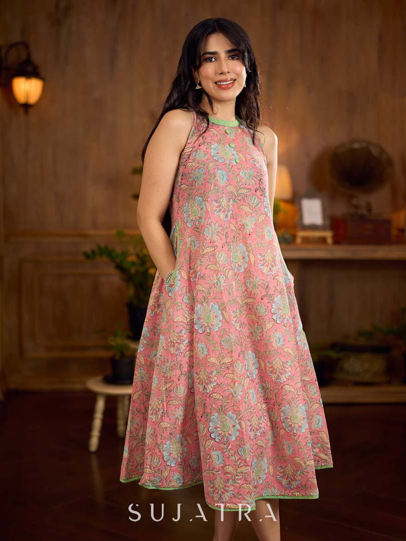 Soft peachy pink floral halter-neck dress with fresh green accents, crafted in a bias-cut silhouette that creates graceful flow and a fluid drape for an effortless summer look.