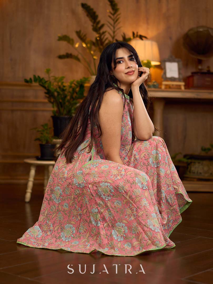 Soft peachy pink floral halter-neck dress with fresh green accents, crafted in a bias-cut silhouette that creates graceful flow and a fluid drape for an effortless summer look.