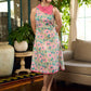 Summer pink floral sleeveless dress featuring an asymmetrical cowl collar and delicate pearl accents, creating a soft, fluid silhouette with a touch of elegant, contemporary charm.