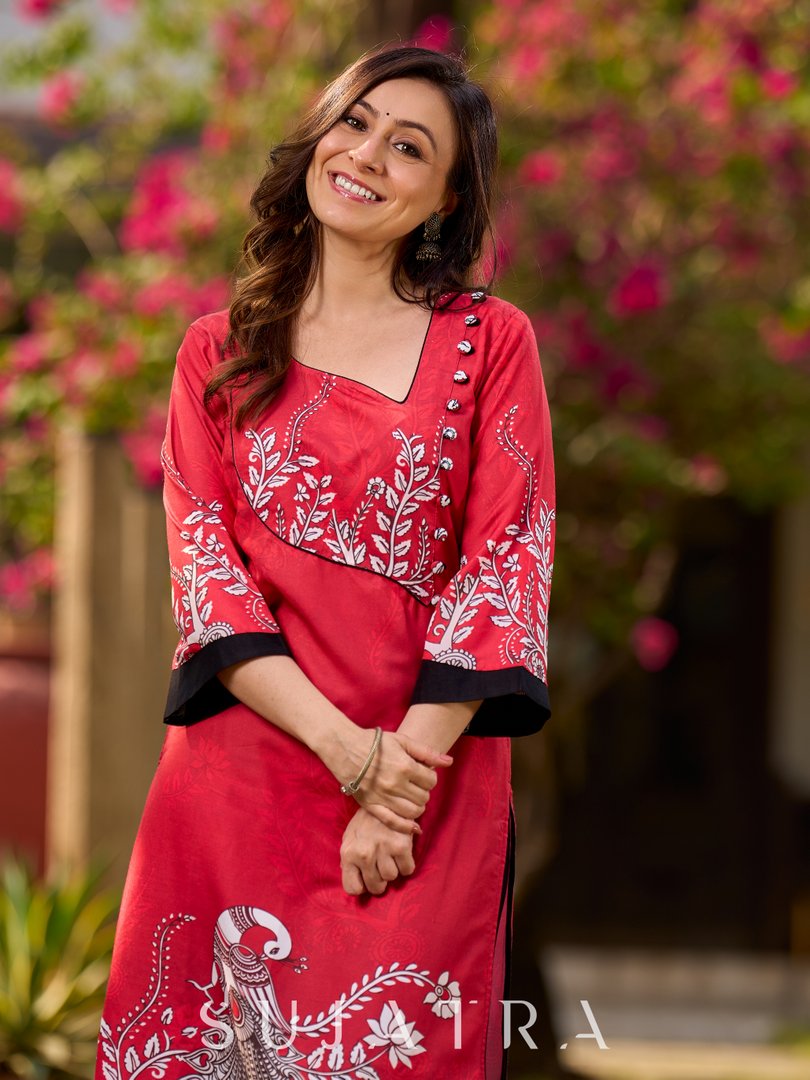 Artisanal red kurta adorned with a Kalamkari peacock motif and a striking asymmetrical neck detail
