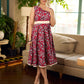 Red Gulmohar floral-printed sleeveless summer dress featuring off-white accents and scalloped lace detailing at the waist, creating a breezy, feminine silhouette perfect for warm, sunlit days.