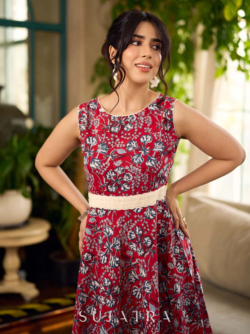 Red Gulmohar floral-printed sleeveless summer dress featuring off-white accents and scalloped lace detailing at the waist, creating a breezy, feminine silhouette perfect for warm, sunlit days.