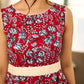 Red Gulmohar floral-printed sleeveless summer dress featuring off-white accents and scalloped lace detailing at the waist, creating a breezy, feminine silhouette perfect for warm, sunlit days.