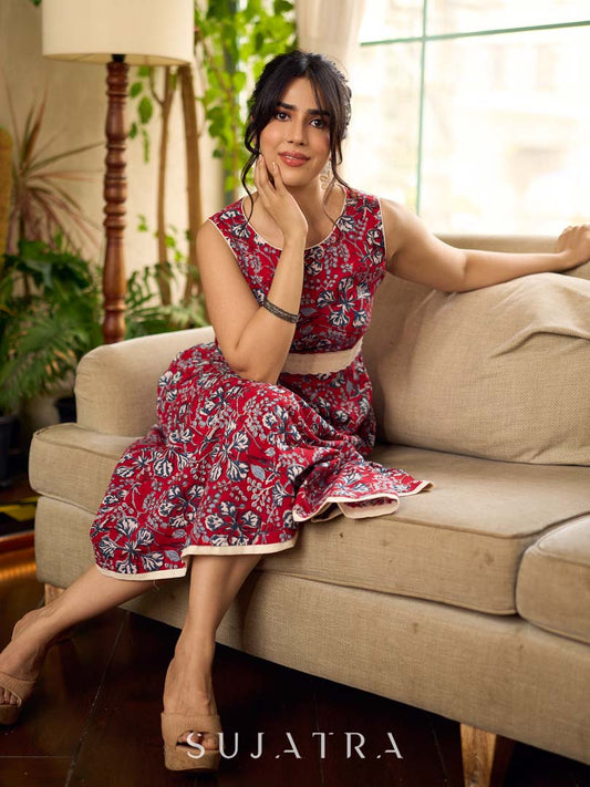 Red Gulmohar floral-printed sleeveless summer dress featuring off-white accents and scalloped lace detailing at the waist, creating a breezy, feminine silhouette perfect for warm, sunlit days.