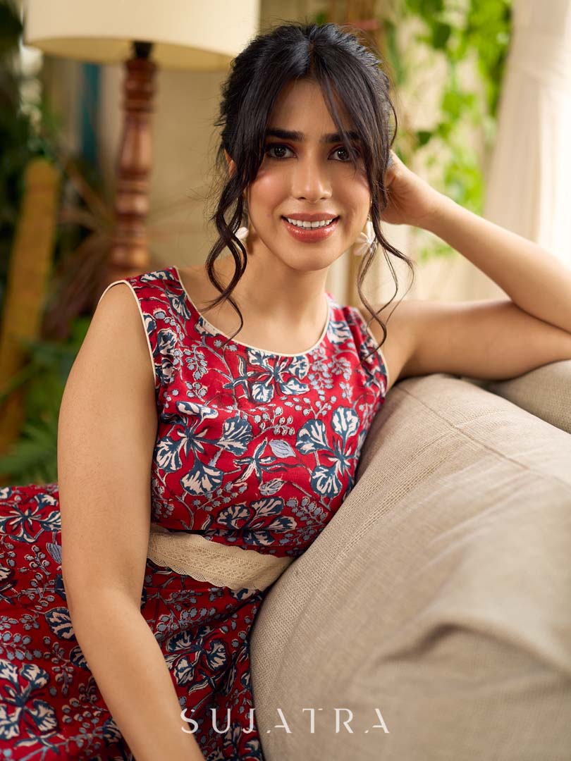 Red Gulmohar floral-printed sleeveless summer dress featuring off-white accents and scalloped lace detailing at the waist, creating a breezy, feminine silhouette perfect for warm, sunlit days.