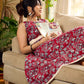 Red Gulmohar floral-printed sleeveless summer dress featuring off-white accents and scalloped lace detailing at the waist, creating a breezy, feminine silhouette perfect for warm, sunlit days.