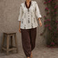 Off-white floral printed top with brown ruffled collar, button front, tie-up sleeves, tassel details, and contrast accents.