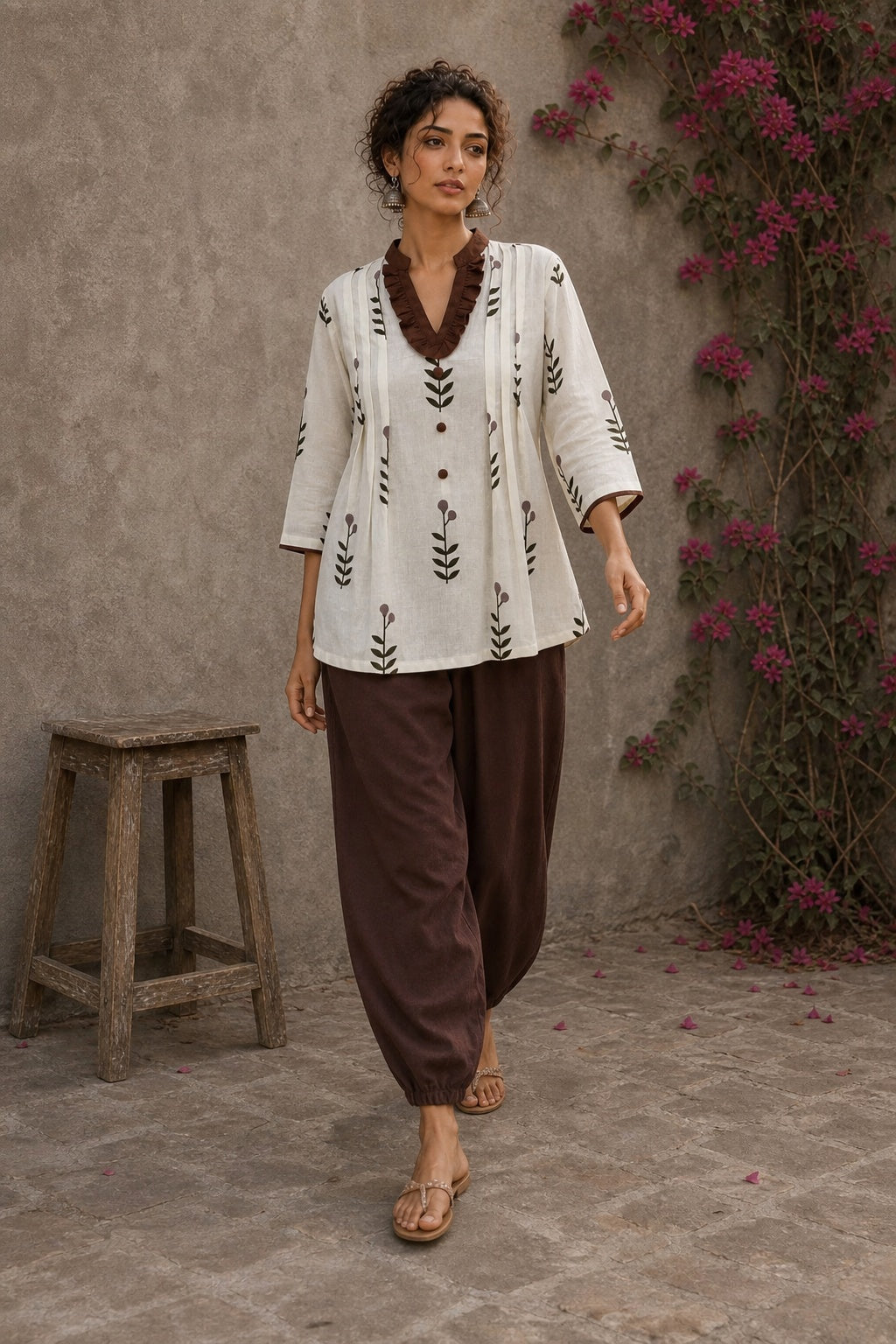 Off-white floral printed top with brown ruffled collar, button front, tie-up sleeves, tassel details, and contrast accents.