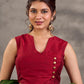 Blouse sans manches en mélange de coton et soie couleur bordeaux, croisée devant de manière asymétrique et agrémentée de boutons dorés