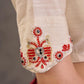 Blouse en coton et soie crème avec encolure et manches brodées de motifs floraux colorés
