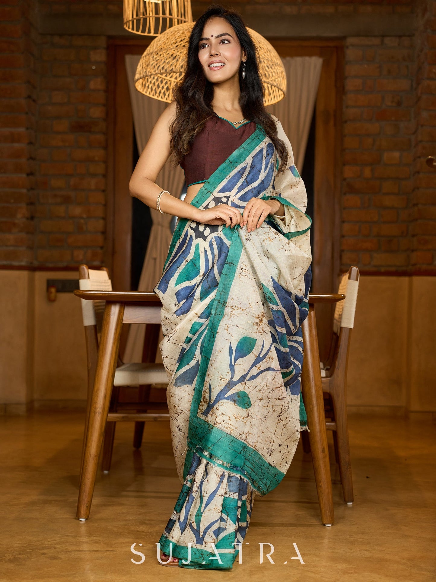 Classic ivory pure silk saree highlighted by teal borders and hand batik artistry
