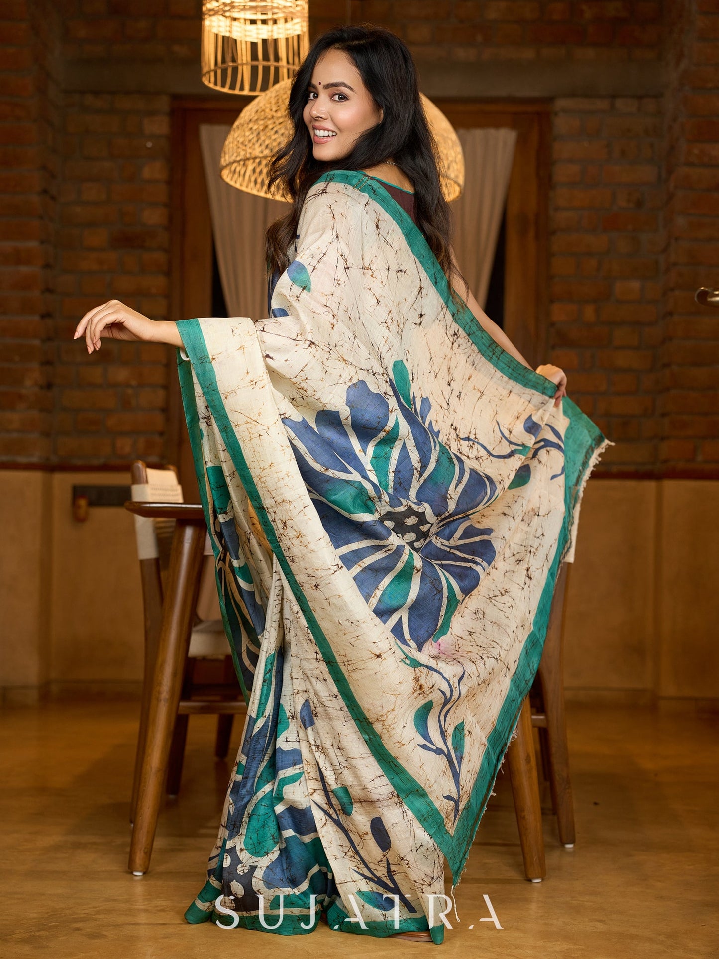 Classic ivory pure silk saree highlighted by teal borders and hand batik artistry