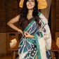 Classic ivory pure silk saree highlighted by teal borders and hand batik artistry