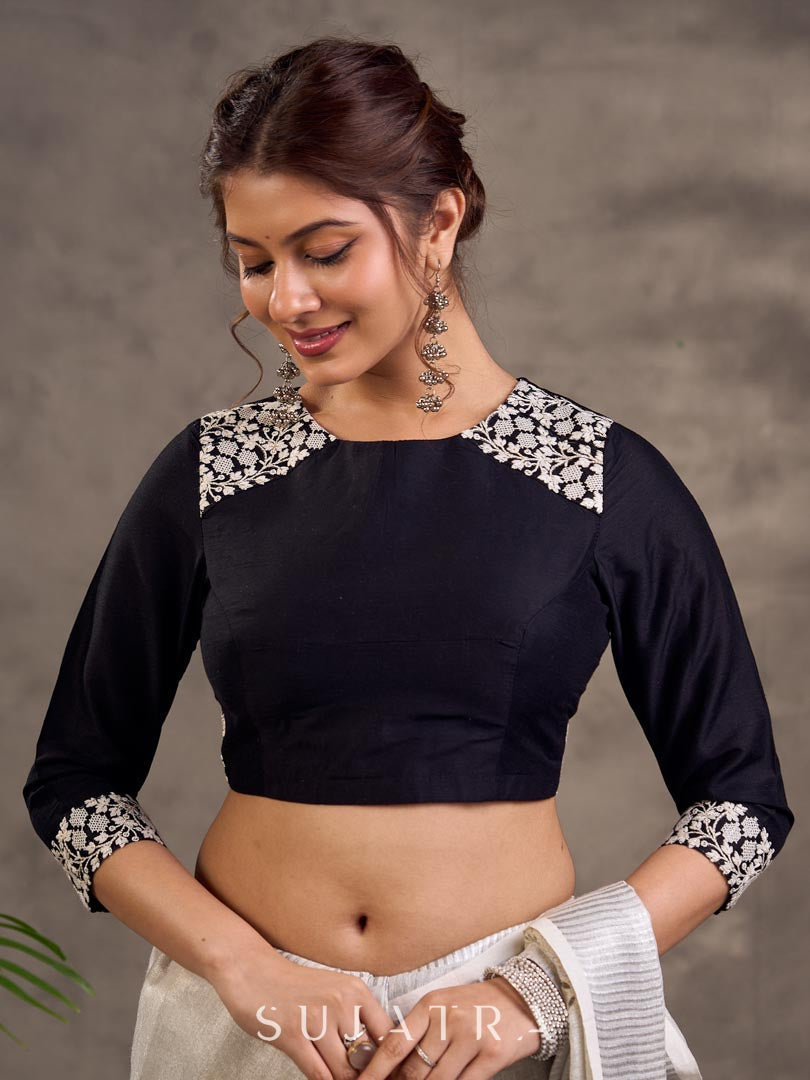 Blouse en soie et coton noir à manches 3/4 avec détails en dentelle brodée florale blanche sur l'encolure et les poignets