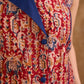 Sharp sleeveless red Kalamkari overlap jacket with a statement one-sided flap, Chinese collar, and navy accents, offering a clean, structured silhouette ideal for elevated corporate styling.