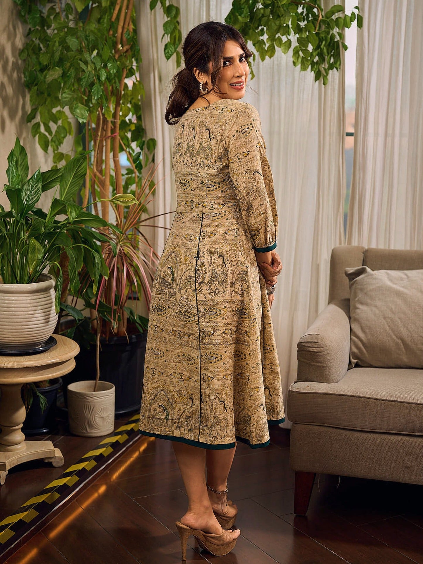 Artisanal beige Madhubani dress featuring intricate motifs, a contrasting green yoke, and refined accents.