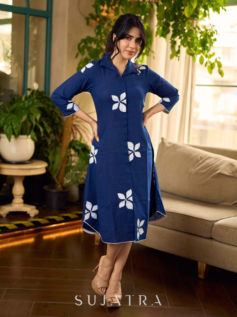 Navy blue apple-cut shirt dress with white floral hand block motifs, conceptually placed and finished with clean white edging and red accents for a refined, contemporary look.
