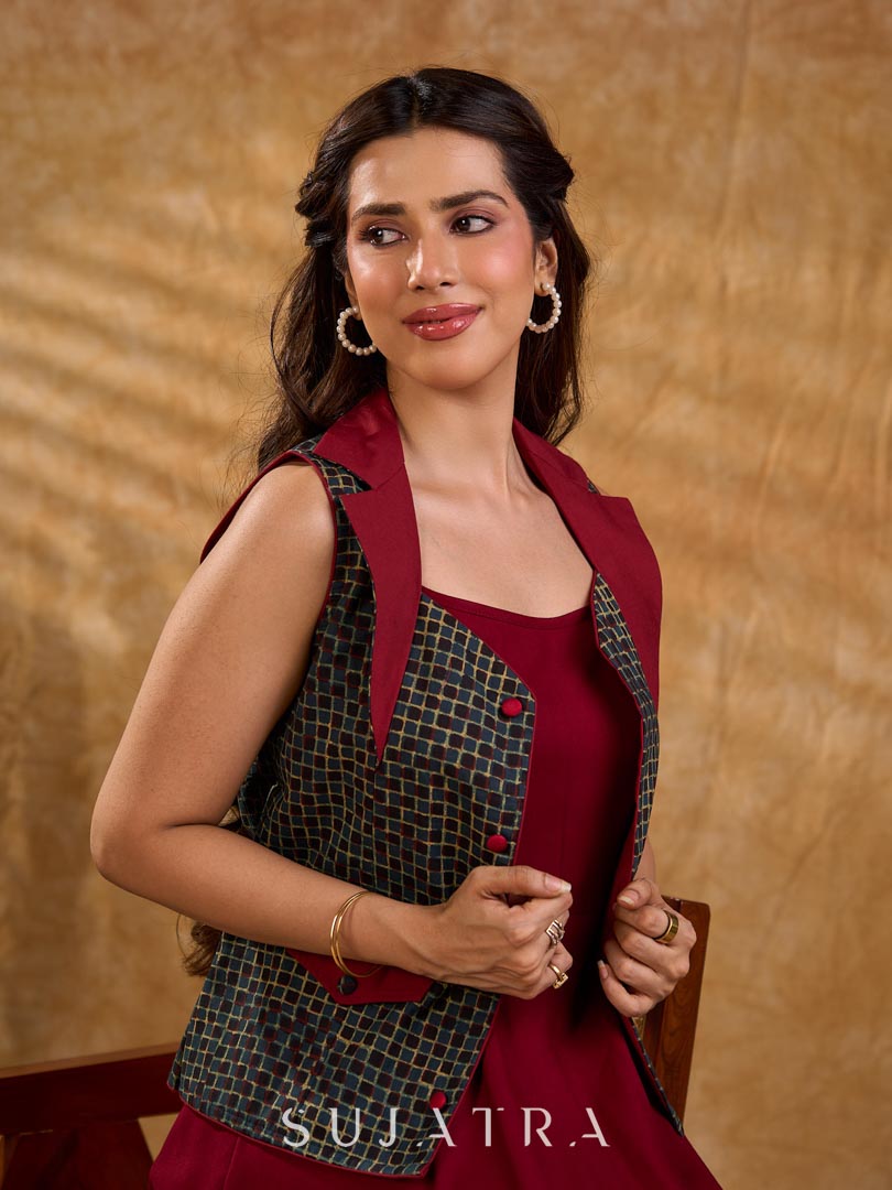 Sharp dark teal and maroon checkered sleeveless jacket with a distinctive notch collar and princess-cut tailoring, offering a structured silhouette ideal for elevated corporate styling.
