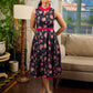 Elegant black Kalamkari dress featuring blooming florals and contrasting pink detailing for refined charm.